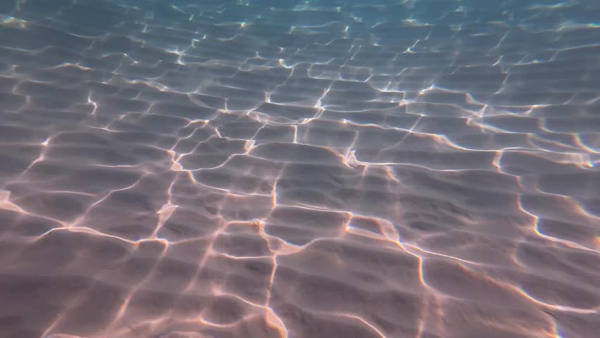 underwater closeup of sand ripples with bright caustics and teal tones, rhythmic light patterns dancing