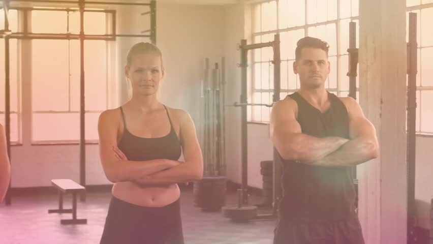Gym team holding arms crossed posing while camera pulling out flare revealing racks for promo. Trio, athletes, instructors, fitness, strength, training, studio