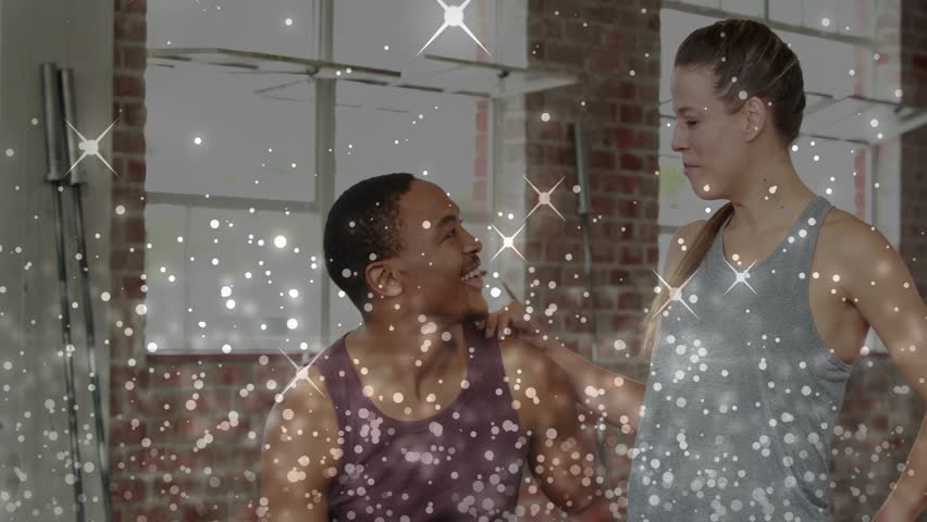 Man looking up and speaking, woman touching then high-fiving, celebrating fitness, glitter overlay. Duo, promo, industrial, gym, loft, camaraderie, energy