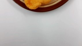 Prawn crackers, known as krupuk, present a golden, airy texture piled on a small brown-rimmed ceramic plate against a bright white surface, suggesting a simple savory snack. - Powered by Shutterstock - Get 15% off with code: PIKWIZARD15