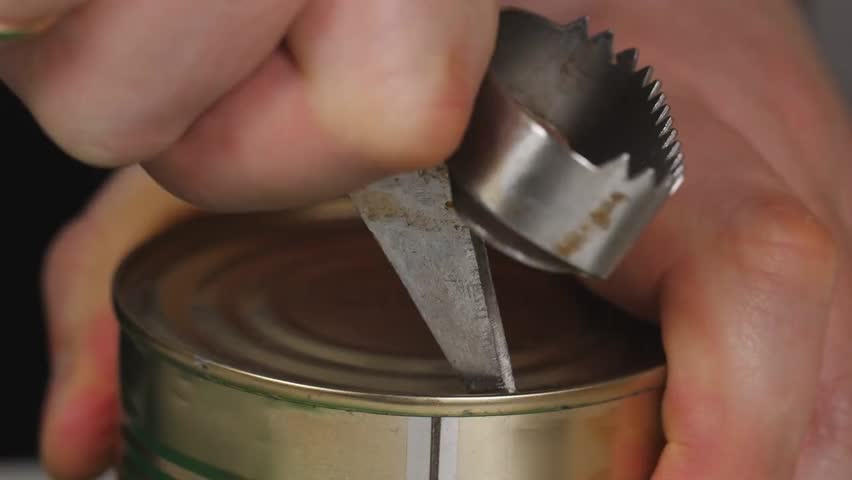 Close-up of a hand using a manual can opener to open a food can, highlighting kitchen tools, cooking preparation, and practical culinary skills.