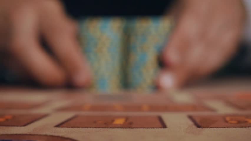 A casino dealer moves a player’s winnings on the table. Highlights gambling, luck, blackjack or poker game, and the excitement of winning in a casino environment.