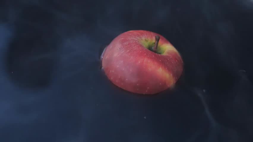 A red apple floats in black steaming water, symbolizing sin, temptation, and punishment. Dark, dramatic close-up conveying mystery, morality, and allegorical storytelling.