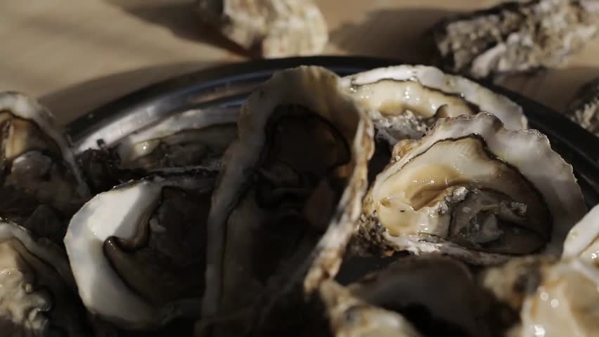Fresh oysters arranged on a bed of ice, showcasing their texture and shine. A clean, appetizing seafood display perfect for culinary, restaurant, or gourmet presentations.