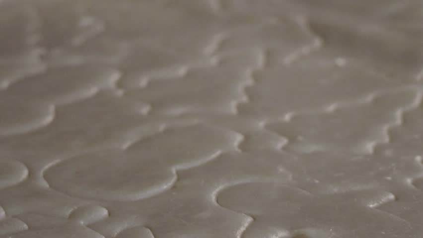 Snowmen, Christmas trees, and other holiday shapes are carved into cookie dough by cookie cutters before being baked.
