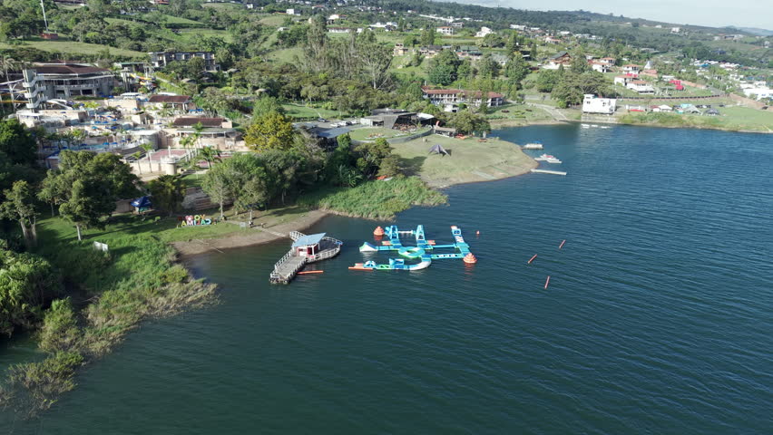 Drone video captures the stunning Lago Calima, highlighting its lush surroundings and vibrant blue waters. The serene, sweeping landscape is perfect for nature enthusiasts.