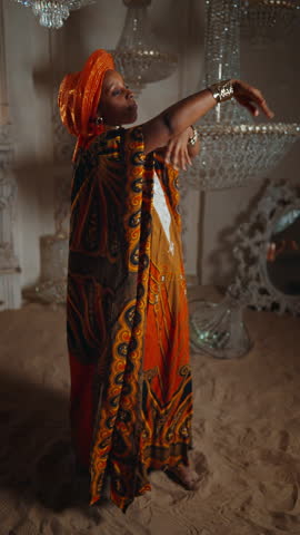 Beautiful African woman in ethnic suit dancing ritual dance in studio, vertical portrait. Unique culture of African tribe, traditions and rituals of Africa, amazing dance show on sand, save heritage