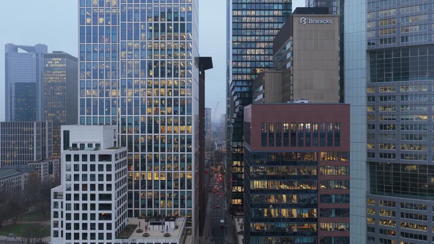 Aerial view of modern office buildings in Frankfurt financial district at dusk, revealing employees working late in illuminated offices