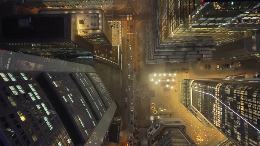 Aerial top down view of the Frankfurt financial district at night. Flying over skyscrapers rooftops and illuminated office buildings