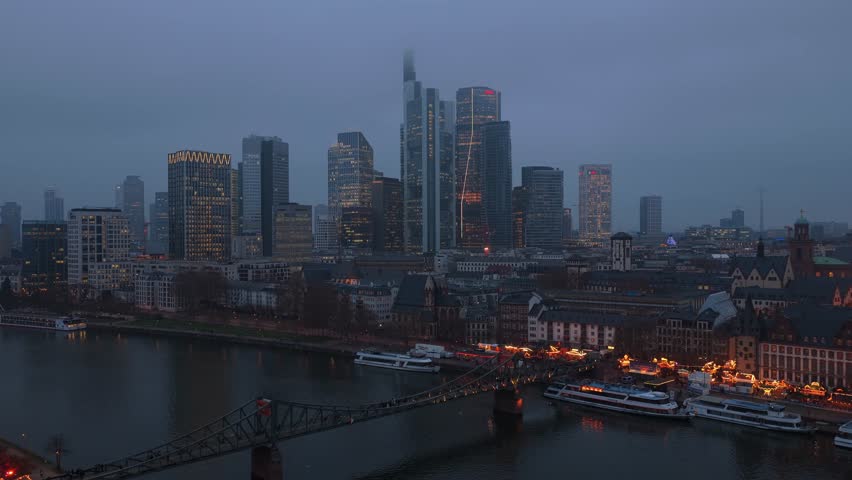 Revealing aerial footage of illuminated Frankfurt am Main skyline with its modern skyscrapers, including the old town and Dreikonigskirche church