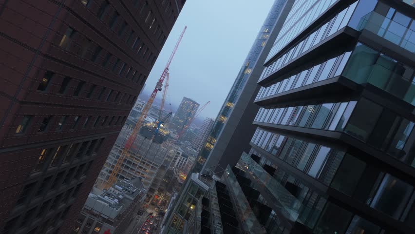 Dutch tilt aerial perspective through financial district of Frankfurt, Germany, modern skyscrapers, illuminated offices and construction site