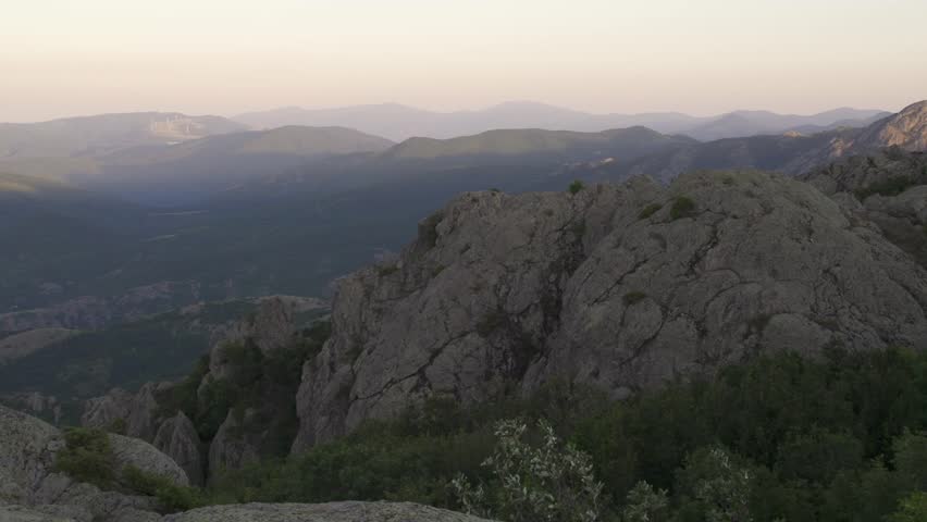 Pan shot captures a view of the Balkan Mountains and Sliven city in the early morning. The warm light spreads across the sky and landscape. Nature reveals its beauty. Stara planina in Bulgaria.
