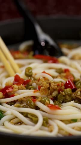 Slow camera move around hot spicy noodle soup bowl under warm restaurant lighting