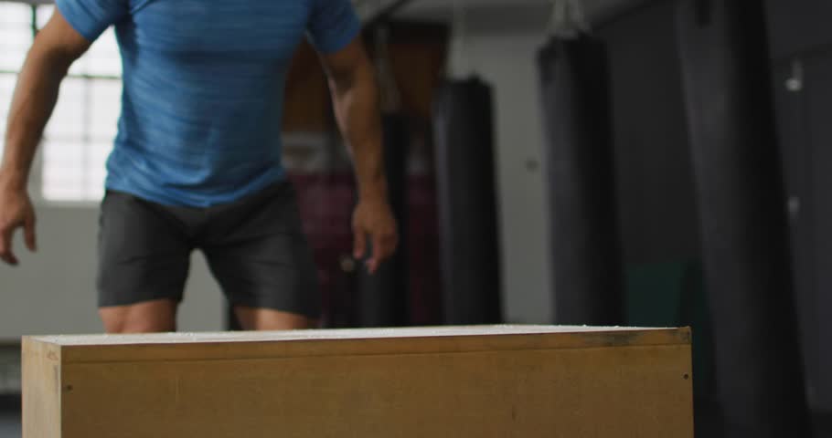 Male athlete readying at plyo box in gym, jumping while HUD charts overlaying worldmap animating. Plyometric, explosive, training, studio, daylight, dust, graphics