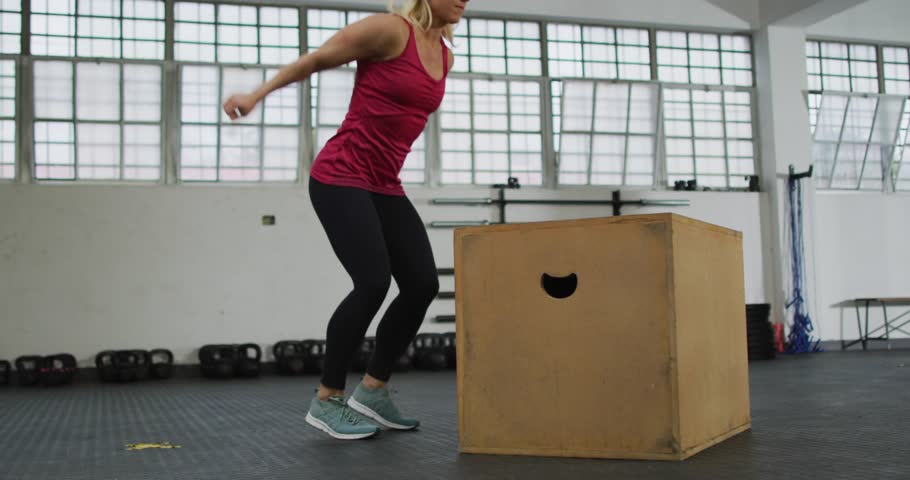 Female athlete doing box jumps for fitness, landing on box initiating floating icons for tracking. Plyometric, gym, explosive, power, dynamic, promo, performance