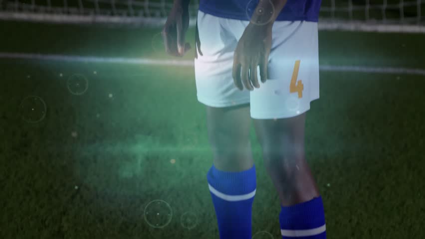 Male soccer player tracking incoming ball in goal, chesting to control play, flares tracking ball. Athlete, promo, cinematic, sports, night, stadium, determination