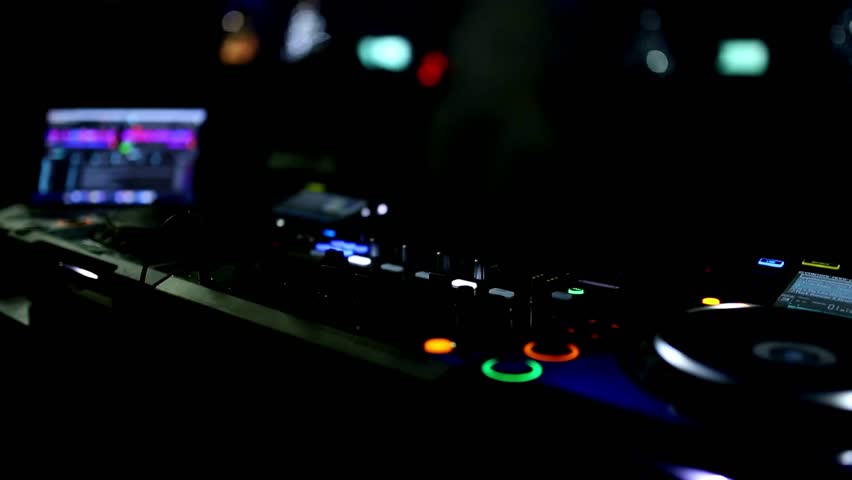 A detailed 4K view of a DJ actively mixing music on a digital mixing console in a dimly lit club or live event setting.