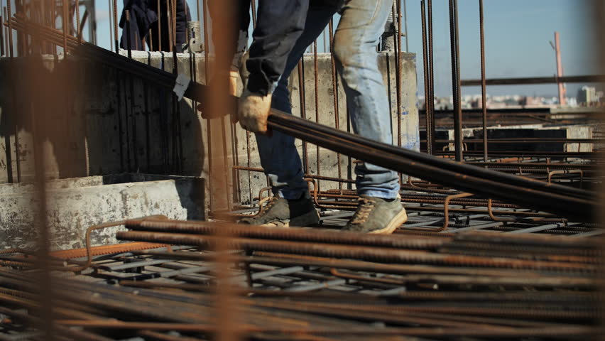 Construction worker placing steel rebar on building site