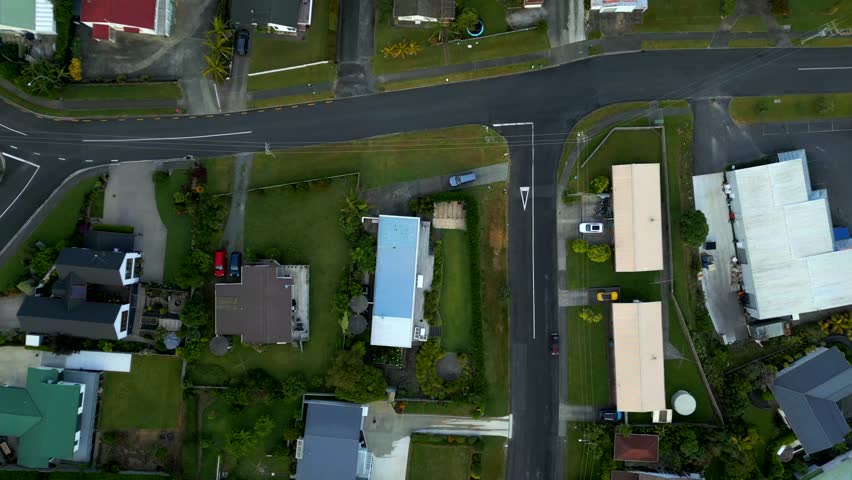Car leaving driveway of property in coopers bay, New Zealand. Aerial top down shot. Large single family houses with green garden on cloudy day in nz.