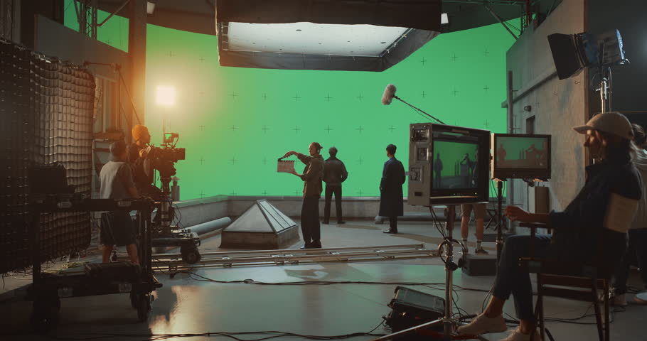 Backstage View of a Professional Movie Set as Crew Operates Camera Dolly, While Actors Perform a Dialogue Scene in Front of a Large Green Screen, Capturing Cinematic Shots