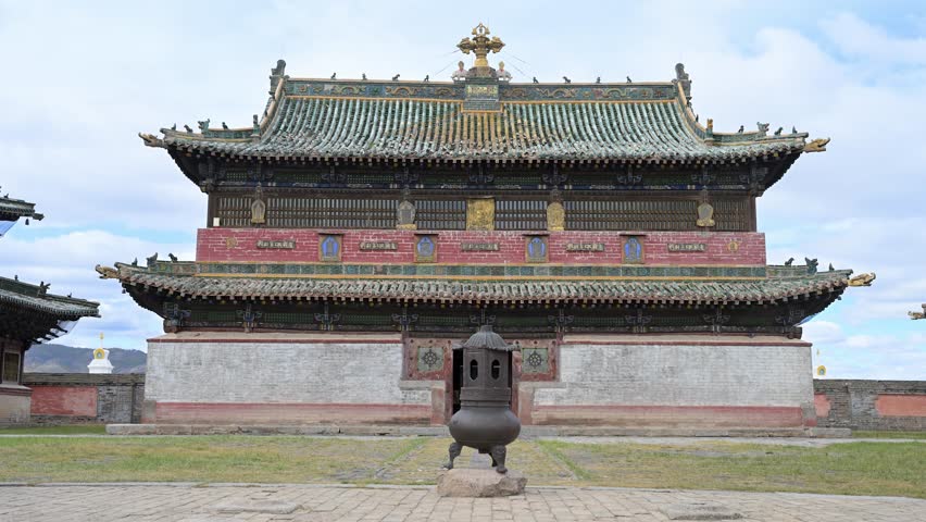 Ornate temple pavilion at Erdene Zuu Monastery, Mongolia. A golden Dharma Wheel and deer sculptures sit atop green tiled eaves, showcasing the artistry of the country