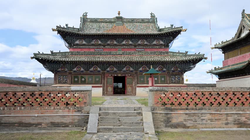Exterior of a temple pavilion at Erdene Zuu Monastery, Mongolia. A golden Dharma Wheel and deer adorn the green tiled roof, highlighting the 16th-century Buddhist artistry of this historic site.