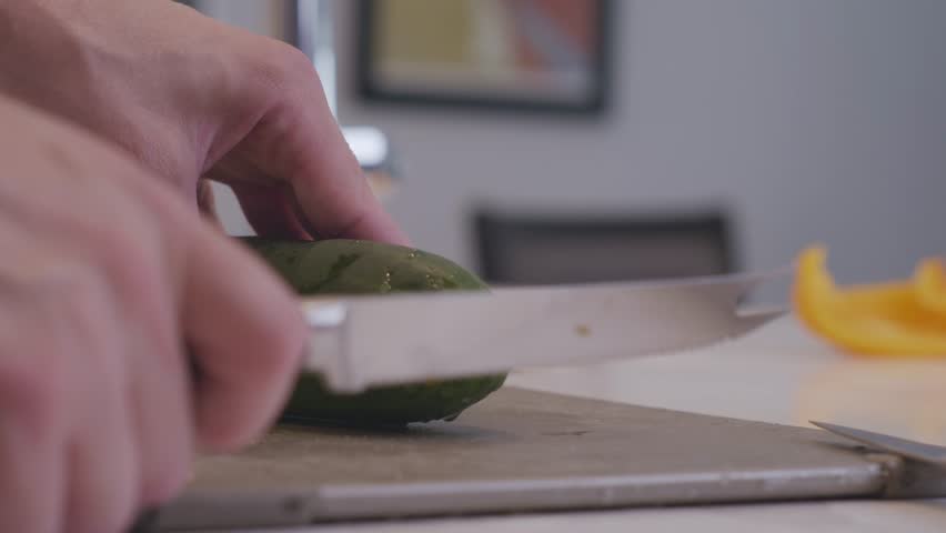 A slow motion shot of a cucumber being cut into thin slices