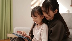 Young Asian mother and her cute daughter using a digital tablet together at home, learning and playing - Powered by Shutterstock - Get 15% off with code: PIKWIZARD15