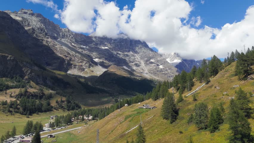 Rising up aerial drone view of pine trees and mountains in Valtournenche, Aosta Valley, Valle d’Aosta, showing the alpine landscape