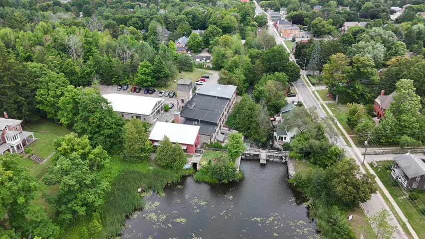 Aerial view of the historic Alton Mill in Alton, Ontario, surrounded by lush trees, heritage homes, and the millpond, showcasing the village’s cultural and architectural charm.