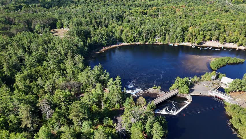 Aerial shot of High Falls in Bracebridge, Muskoka, showing the Muskoka River, forested shoreline, churning water, and country surroundings in Ontario up-north destination.