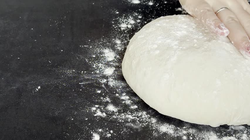 Close up of female hands kneading and preparing yeast dough on the table, making round ball for resting 