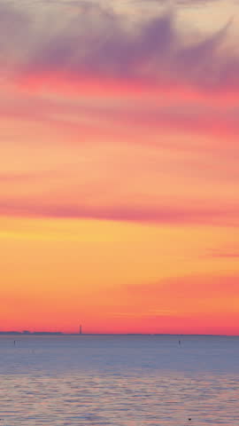 Sunset over ocean with two buoys on the water. The sky is painted in orange and pink tones, which creates a serene atmosphere. a bird flies against the background of a bright sunset sky.