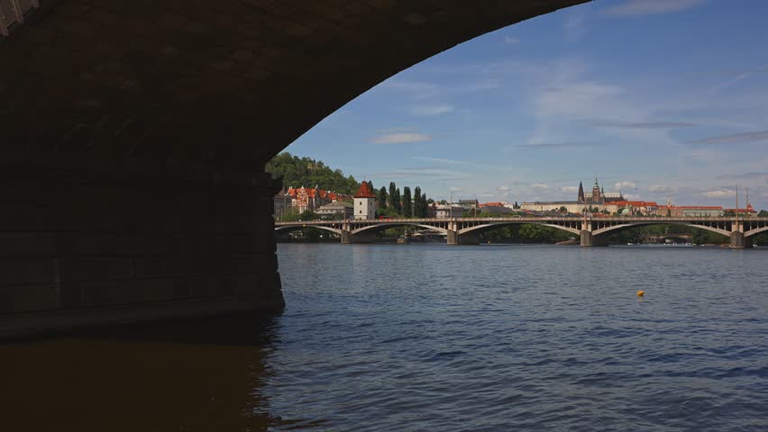 Arch view of historic Prague Castle complex across river.