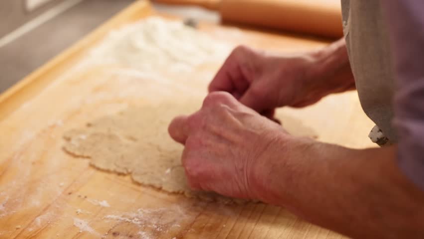 Hands cutting cookie shapes from rolled dough showing real Christmas baking preparation