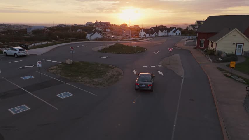 Cinematic Aerial View Capturing Peggys Cove Lighthouse Near Halifax, Nova Scotia, During Sunset, With Warm Light Touching The Rocky Shore, Soft Reflections On Granite Surfaces, And Atlantic Landscape