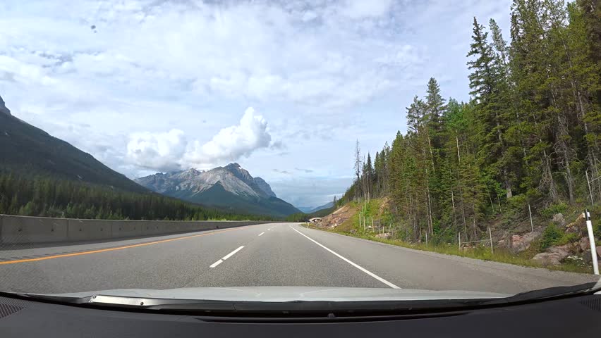 Breathtaking mountain views accompany a smooth drive along a well maintained highway, showcasing the natural beauty of the canadian rockies near banff national park