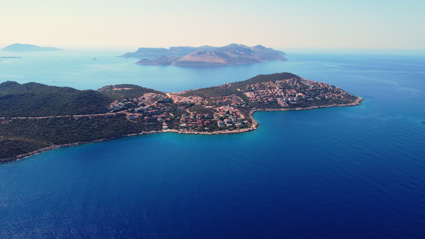 Aerial drone approach to a luxury peninsula with upscale villas in Kas, Turkey. Premium seaside lifestyle, luxury real estate and elite travel destination concept.