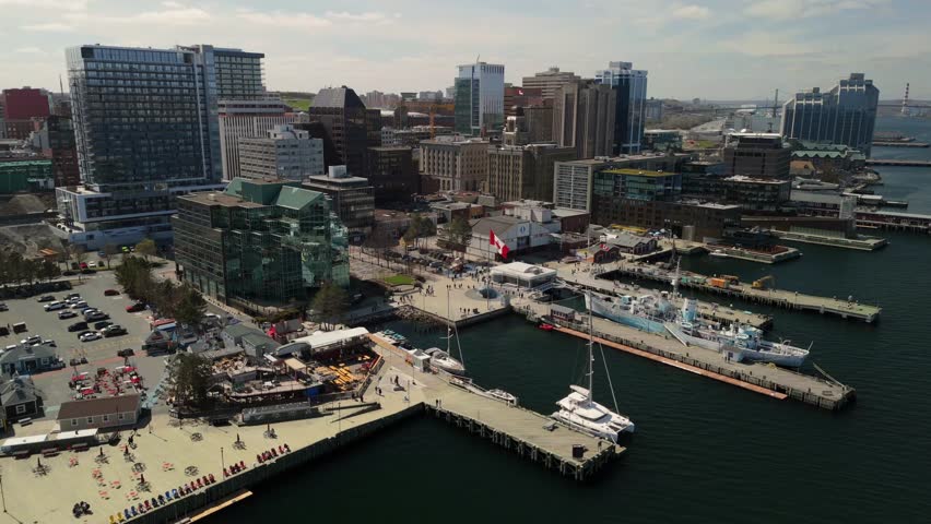 Aerial Footage Highlights The Halifax Nova Scotia Skyline With Modern Towers A Busy Waterfront Yachts In The Harbor And Tourists Walking Through The Sunlit Promenade During A Clear Summer Afternoon