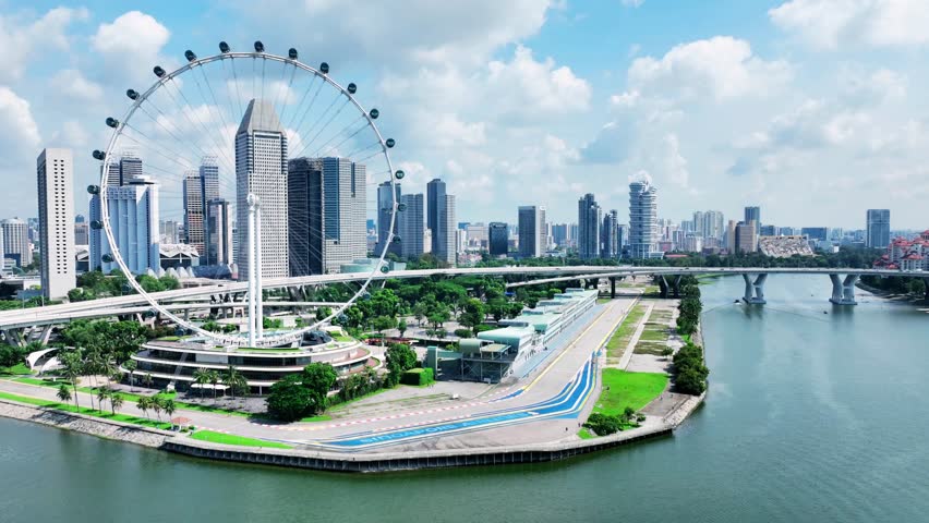 Aerial drone shot of the Singapore Flyer near Marina Promenade, showcasing the giant observation wheel, waterfront area, and modern city skyline in the background.