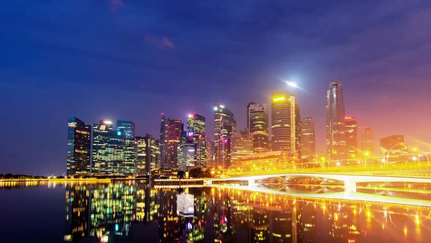 Night-to-day time-lapse of Jubilee Bridge at Marina Bay, Singapore, showing modern buildings, waterfront, and city skyline transitioning from night lights to daylight.