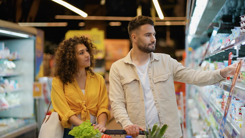 Young couple choosing yogurt shopping in supermarket