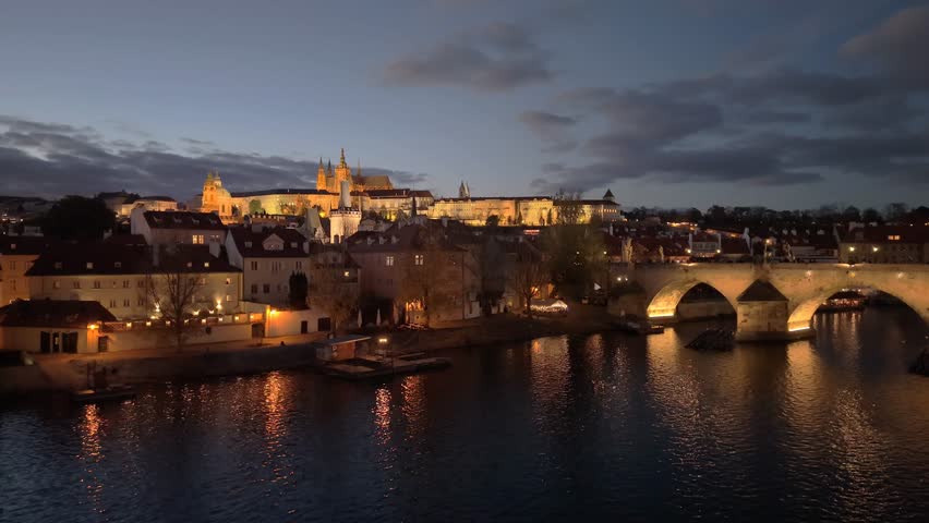 Aerial views of Prague showcase the stunning city skyline at dusk. Illuminated landmarks like Prague Castle and Charles Bridge reflect on the Vltava River, creating a magical atmosphere.