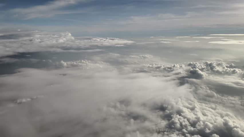 An aerial view of a vast sea of clouds, taken from a high altitude from an airplane window.
