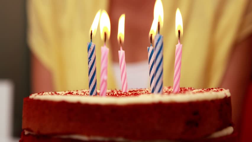 Gold confetti falling cake five lit candles hand holding lighter moving closer preparing blowout. Celebration, anticipation, festive, warm, kitchen, decor, glitter