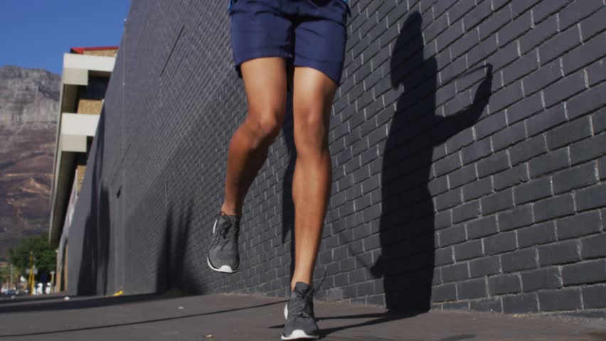 man skipping rope by brick wall for fitness promo, camera tilting revealing NEW SEASON turning gold. Athlete, outdoor, urban, cardio, motion, shadow, street