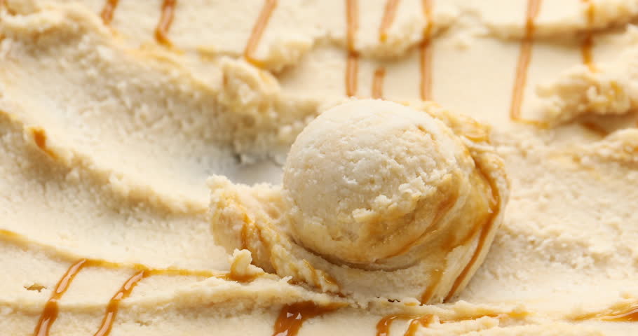 Pouring caramel sauce onto tasty ice cream, closeup