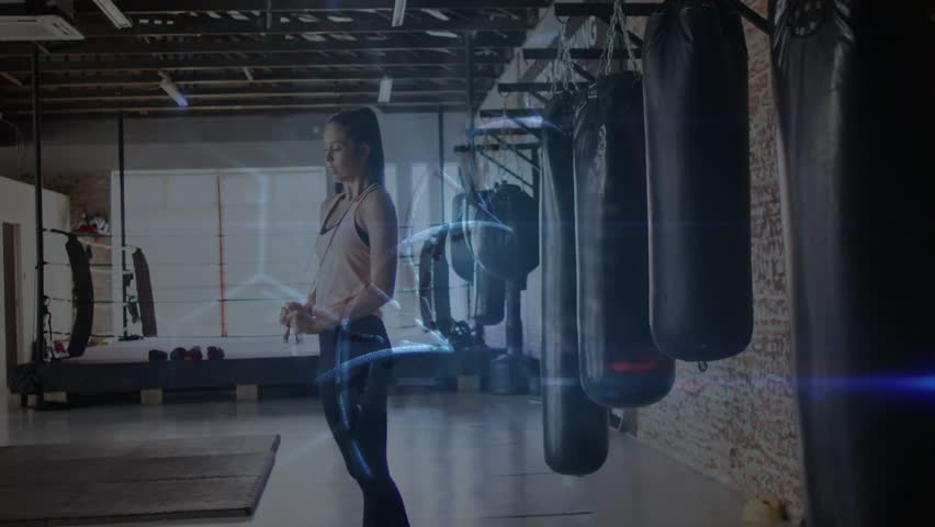 Woman holding jump rope, rotating rope and causing blue trails revealing IDENTITY, prepping workout. Boxing, gym, training, fitness, focus, strength, equipment