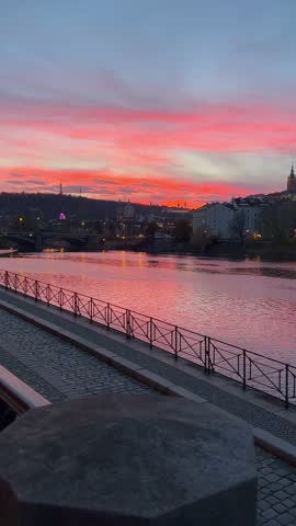 A view from the embankment on the historical buildings of Lesser town (Mala Strana) across the river during colourful sunset. Prague, Czech Republic 