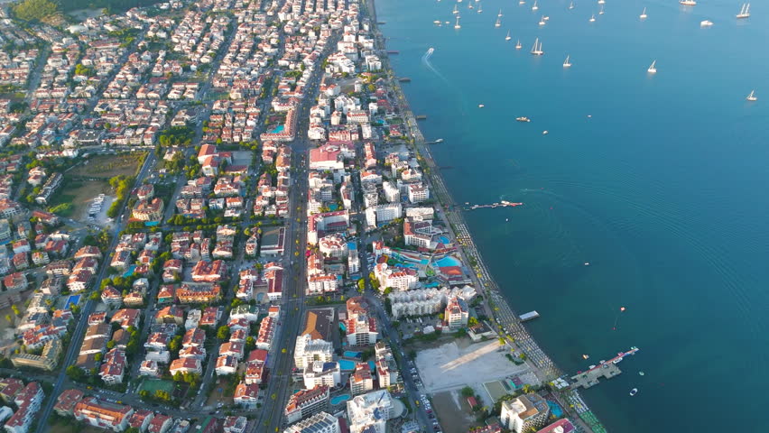 Marmaris, Turkey. Urban beaches line along Marmaris Bay with yachts and city during sunset. Sandy coastline with golden hour lighting and city backdrop. Aerial View